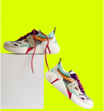 Tênis branco com detalhes azul, verde, marrom e vermelho apoiado em uma caixa branca.