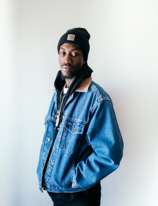 Modelo masculino com Jaqueta jeans com bolsos laterais e gorro preto.