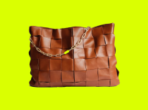 Bolsa na cor marrom com alça de corrente com detalhe verde.